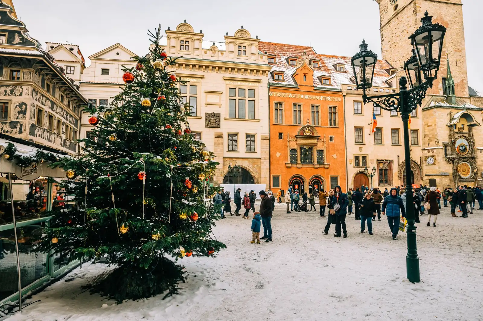Decorated Christmas tree and market stalls on a snowy Old Town Square in Prague