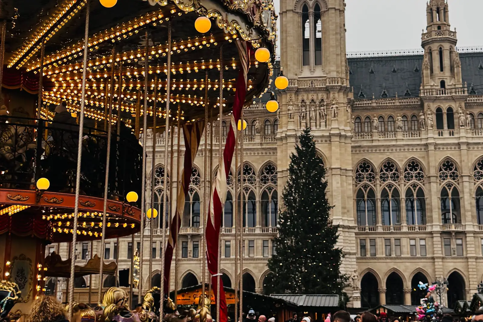 Lit carousel and crowds at the Christmas market in front of Vienna City Hall
