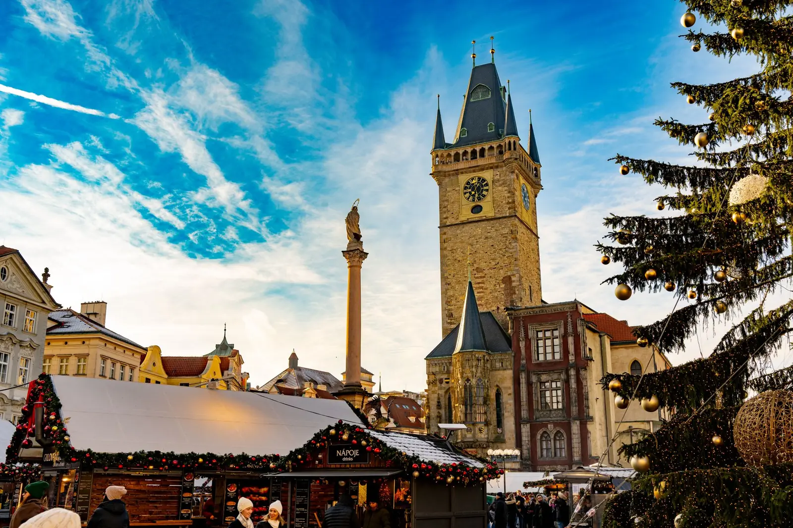 Christmas market stalls and a decorated tree on Prague Old Town Square below the Old Town Hall tower