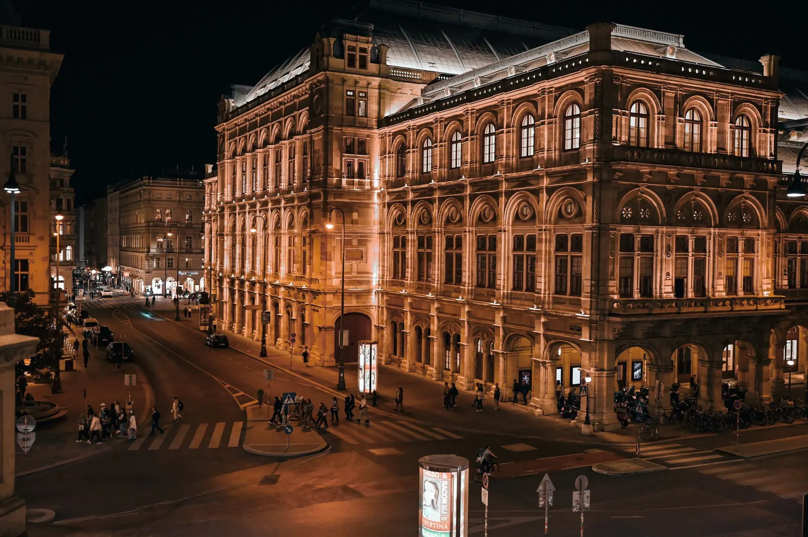 Vienna State Opera house illuminated at night with traffic on the Ring